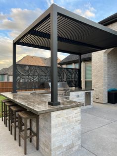 an outdoor kitchen with bar seating and grill