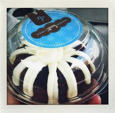 a person holding up a cake in a glass container with white icing on it