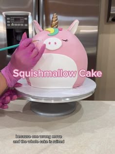 a woman is decorating a pink unicorn cake