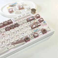 a white keyboard with brown and pink keys sitting on a table next to a controller