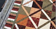 a close up of a quilt on a wooden table with an orange and brown design