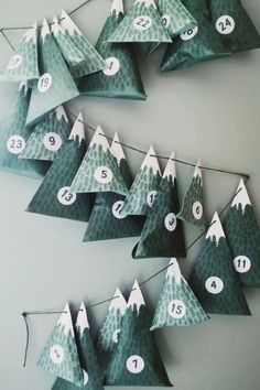 paper christmas trees are hanging on the wall with numbered numbers and snow - capped tops