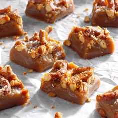 several pieces of dessert sitting on top of wax paper covered in nuts and pecans