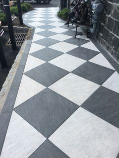 a black and white checkerboard sidewalk with people sitting on benches in the background