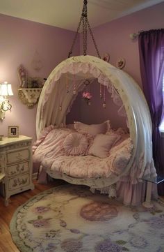 a canopy bed is in the corner of a room with pink walls and purple curtains