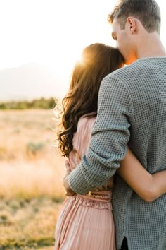 a man and woman embracing each other in an open field