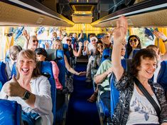 a group of people riding on the back of a bus with their arms in the air