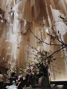 a vase filled with flowers sitting on top of a table next to a wall hanging from the ceiling