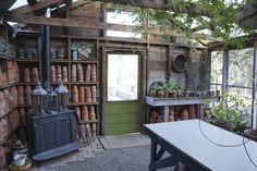 a room filled with lots of potted plants and pots on shelves next to a table