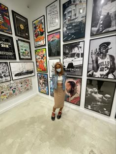 a woman standing in front of a wall full of pictures and posters on the walls