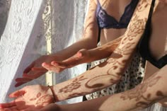 two women with henna tattoos on their arms and one woman holding her hands out