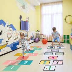 two children playing in a play room with numbers on the floor