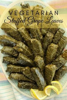 stuffed grape leaves on a white plate with lemon wedges in the middle and title vegetarian stuffed grape leaves