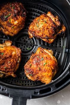 four pieces of chicken in an air fryer with herbs on the top and bottom