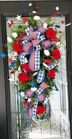 a patriotic wreath with red, white and blue flowers on the front door for memorial day