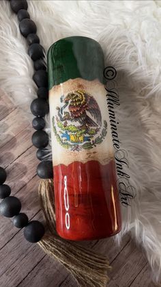 a red and green bottle sitting on top of a wooden table next to a black beaded necklace