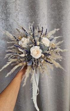 a bridal bouquet being held by a woman's hand on a gray background