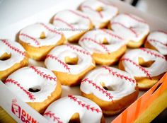 a box filled with white frosted donuts covered in icing and baseball designs