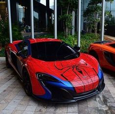 two red and blue sports cars parked next to each other in front of a building