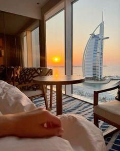 a bedroom with a view of the burj tower in the distance, and someone's hand resting on the bed