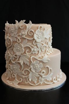 a three tiered cake with white frosting flowers and scrolls on the bottom layer