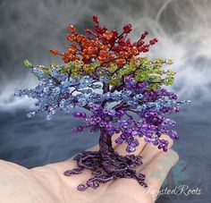 a hand holding a miniature tree made out of beads