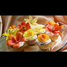 cupcakes decorated with colorful flowers on a glass platter, ready to be eaten