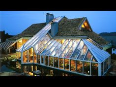 a house with a green roof that has glass walls and is lit up at night