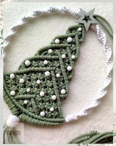 a crocheted christmas tree ornament with white balls and green yarn on it