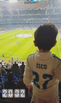 a young boy watching a soccer game from the stands at a stadium with people sitting in seats