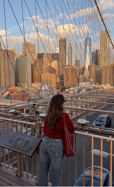 a woman standing on top of a bridge looking at the city