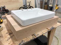 a white sink sitting on top of a wooden table next to a pair of tools