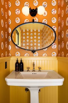 a bathroom sink sitting under a mirror in front of a wall mounted faucet