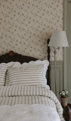 a bed sitting next to a lamp on top of a night stand in a bedroom