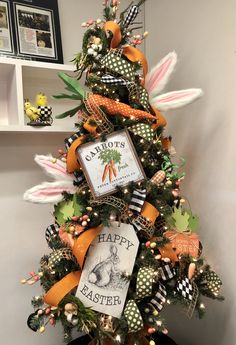 a decorated christmas tree with an orange ribbon and some carrots on it's top