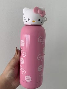 a hand holding a pink hello kitty water bottle