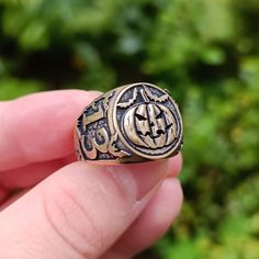 a person is holding a ring in their left hand and there are green plants behind them