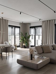 a living room filled with lots of furniture and large windows covered in draping