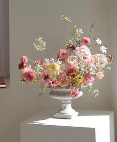 a vase filled with lots of pink and white flowers on top of a table next to a window