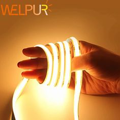 a hand holding a light that is on top of a white surface with the words welpur above it