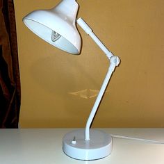 a white desk lamp sitting on top of a table next to a brown and yellow wall