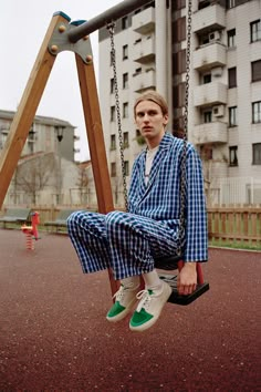 a man sitting on top of a wooden swing