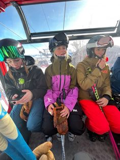 three skiers sitting in the back of a ski lift