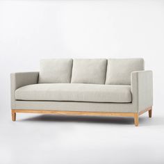 a light gray couch with wooden legs and armrests, against a white background