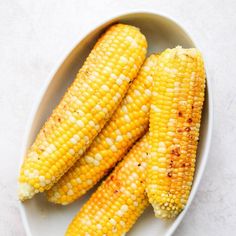 grilled corn on the cob in a white bowl