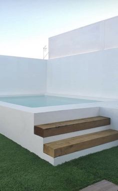 an outdoor hot tub with steps leading up to the pool and grass on the ground