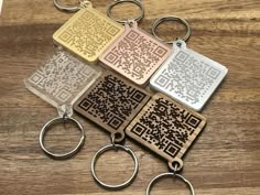 four keychains with different designs on them sitting on top of a wooden table