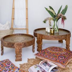 two wooden tables sitting next to each other on top of rugs and pillows in front of a mirror