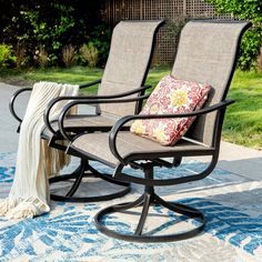 two patio chairs sitting on top of a blue and white rug next to a tree