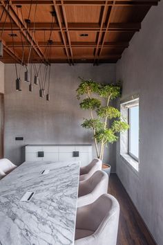 a kitchen with marble counter tops and white chairs in front of a large table that has a potted plant on it